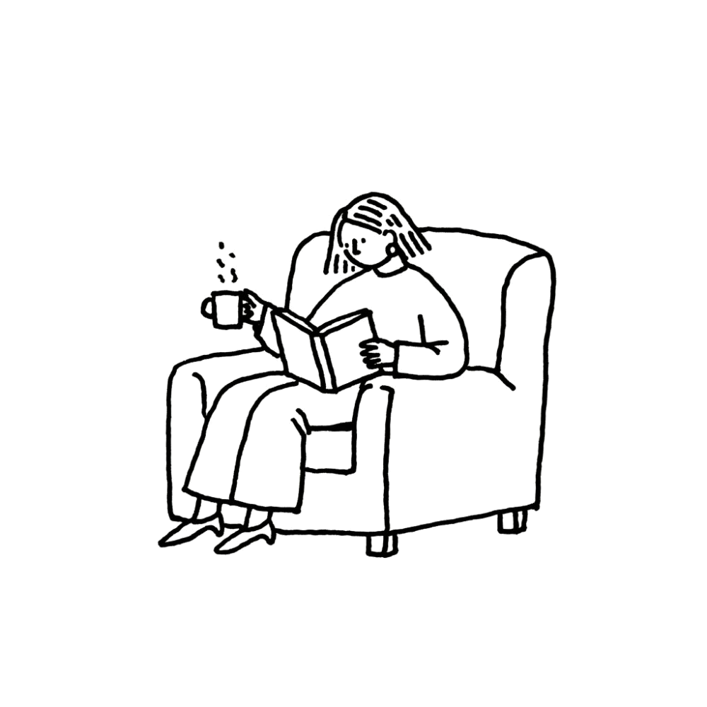 A reader relaxing in an armchair with a book and a hot drink